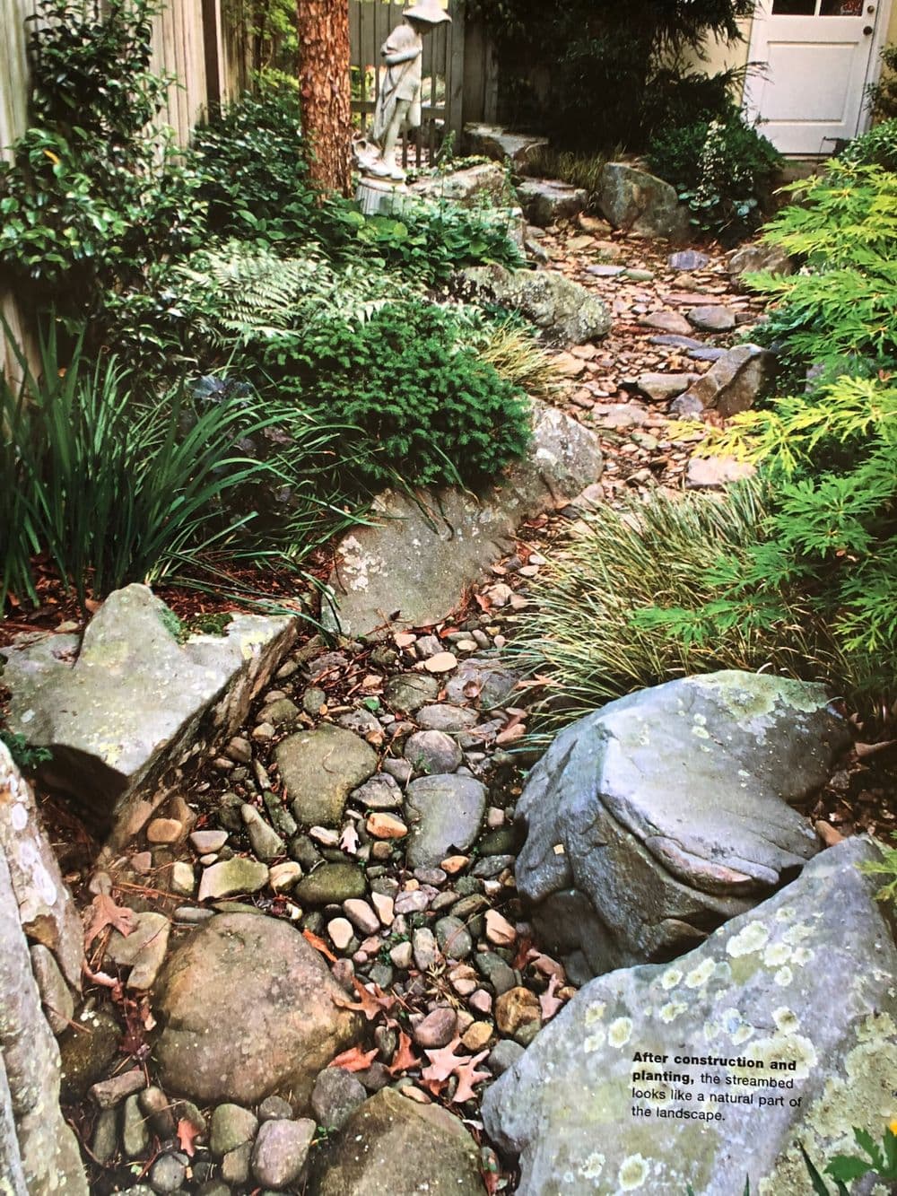 Rocky garden pathway surrounded by lush greenery and natural stone features.