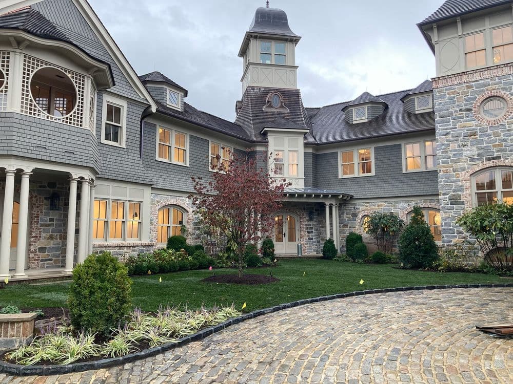 Elegant stone mansion with a tower, manicured lawn, and cozy courtyard garden.